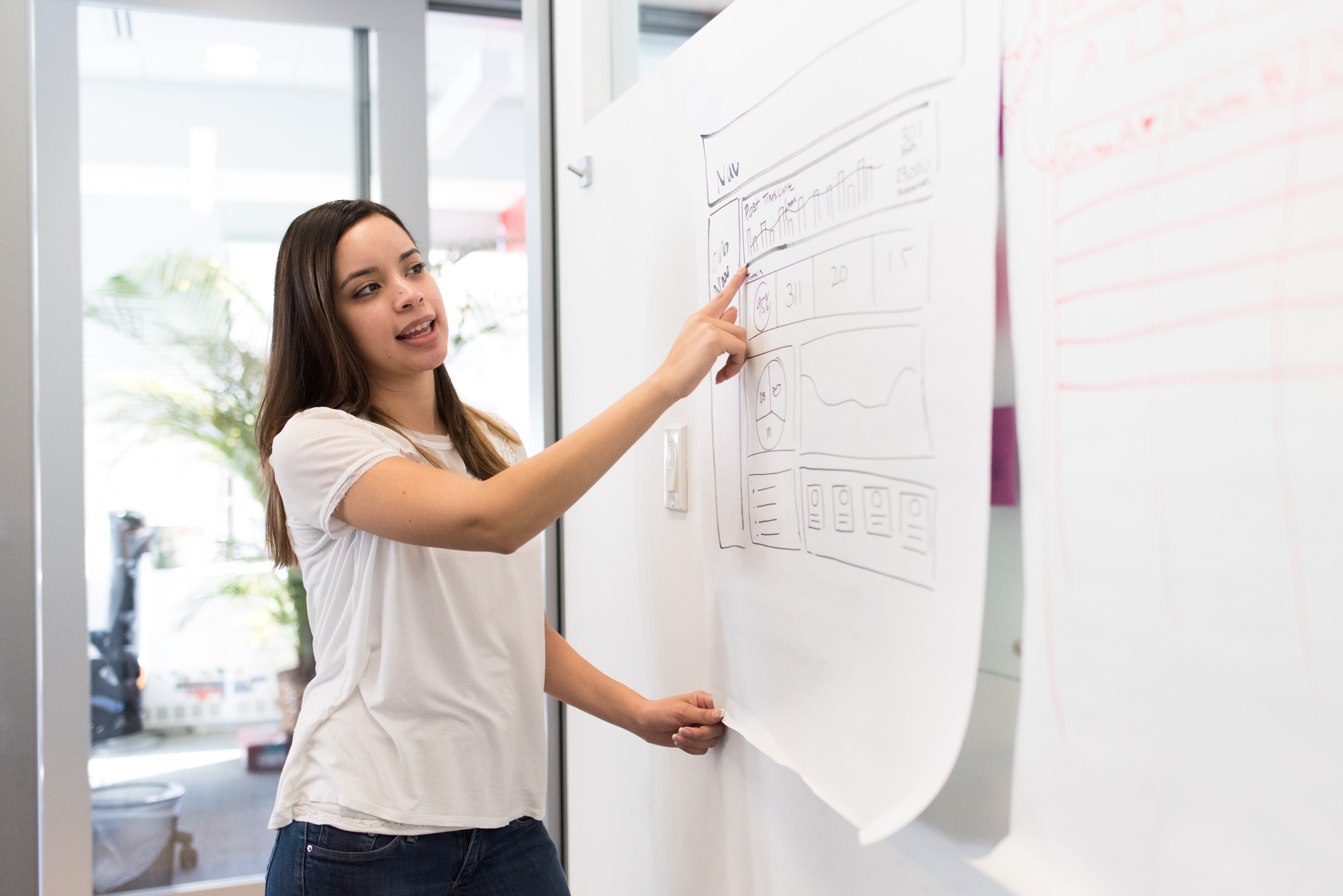 Female NetSuite professional pointing to a project plan on a white board